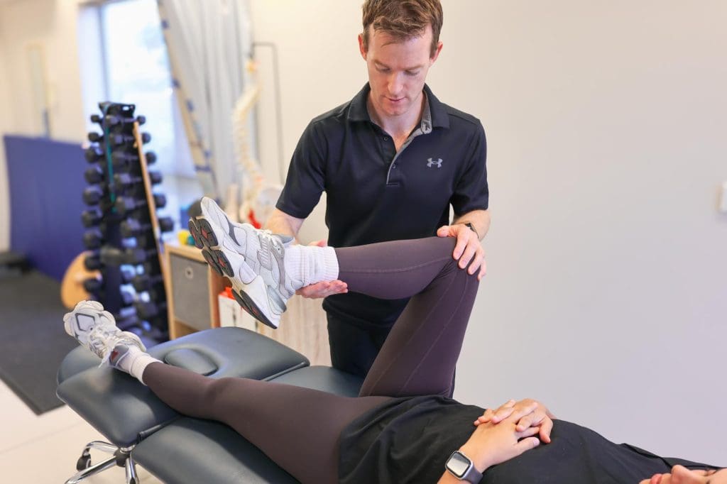 Physiotherapist guiding client through a shoulder mobility assessment in clinic.