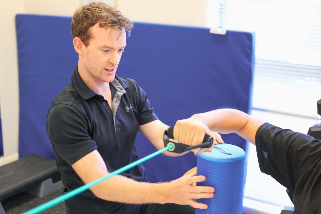 Physiotherapist guiding client through resistance band exercise during a functional assessment in clinic