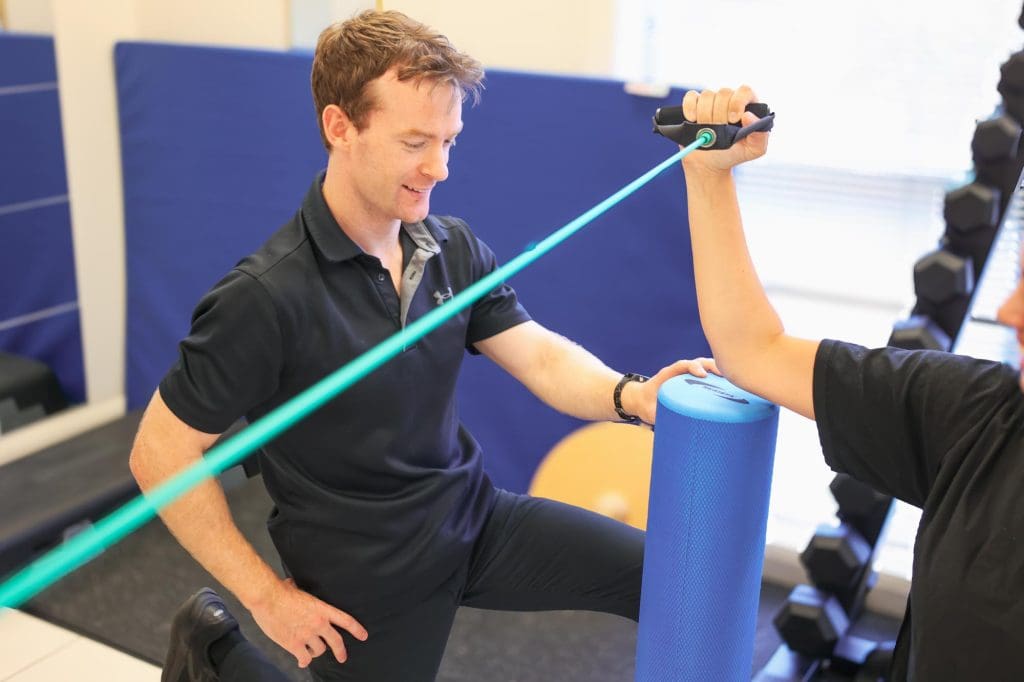 Physiotherapist demonstrating correct lifting technique to client during workplace assessment