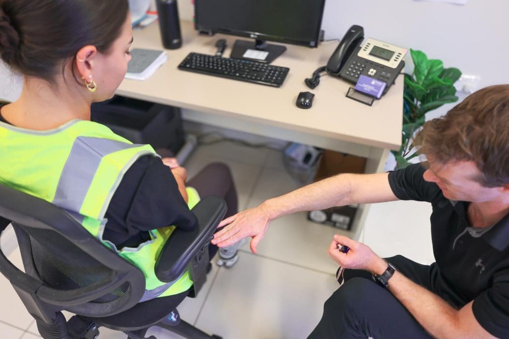 Physiotherapist coaching client through a functional strength exercise during assessment in clinic